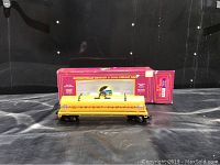 Yellow O scale Union Pacific freight car with visible detailed markings and dome cover on black wheels, displayed in front of original red box with text describing model features.