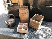 Photo showing cast kettle, wooden nail barrel, and two wooden boxes on a black surface.