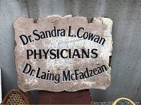 Front view of old physicians wooden sign with visible text and weathering.