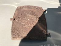 Cast iron door showing surface rust and embossed 'Pat D 1876' with decorative elements