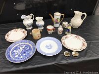 Image of all 15 pieces laid out on a black background, shows variety of plates, pitchers, teapot, and small jars.