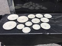 Full overview of the 13-piece dish set including full plates and smaller plates laid out on a black surface.