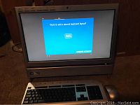 Front view of Acer all-in-one computer powered on, showing setup screen with keyboard and mouse placed in front
