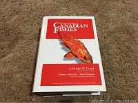 Cover photo of book titled 'Encyclopedia of Canadian Fishes' with orange fish illustration on front dust jacket.