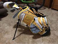 Junior golf set in yellow and white golf bag standing on carpet