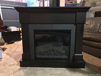 Front view of dark brown wooden mantel electric fireplace with glass panel and simulated logs inside.