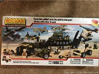 Front of the box showing the military-themed building set with vehicles, aircraft, and soldier figures, indicating over 1000 pieces.