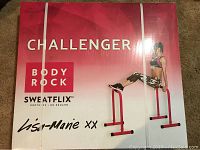Front view of the boxed Challenger Body Rock Sweatflix dip bars showing branding and promotional image.