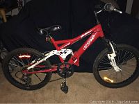 Side profile of the CCM Vandal youth bike showing red and white frame, black saddle, and 20-inch knobby tires.