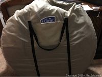 Carrying bag of the EZ Twist pop up tent, beige fabric with the EZ Twist logo and black carrying straps.