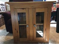 Front view of the solid wood bookcase with two glass doors and round metal knobs.