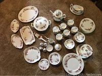Complete lot overview showing arrangement of all bone china pieces on carpeted floor
