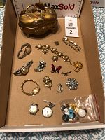Overall lot featuring gold-tone floral jewelry box, assorted jewelry and watches inside a cardboard box