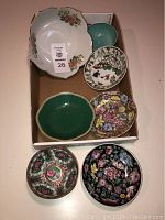 Top view of 7 decorative Asian bowls and dishes displaying their various floral and nature-inspired patterns and colors.