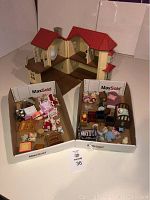 Photo showing open beige and red-roof Calico Critters Manor House and two boxes containing furniture and animal figures.