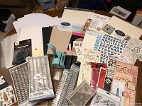 Full view of the lot with scrapbook papers, stickers, binding combs, and binding tool visible