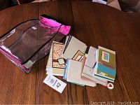 Clear pink vinyl carrying case open showing assortment of handmade cards and envelopes spread out on table.
