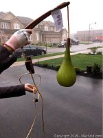 Full view of vintage green glass pendant light fixture showing teardrop glass, wooden arm, and hanging cord