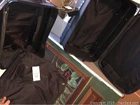 Open large black suitcases showing interior straps and wheels