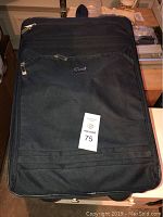 Large black fabric suitcase with front zippered pocket and Ciao logo on front