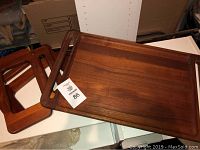 Two stacked vintage wooden breakfast trays, rectangular with rounded edges and cut-out handles, showing smooth wooden surface and warm brown finish.