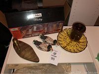Overall lot showing brass duck, wooden ducks, yellow glass dish, brown pot with lid, and boxed Libbey whiskey glass set
