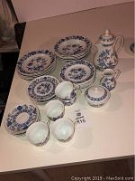 Full set of Czech Bohemian china with Henrietta pattern displayed on a table including plates, cups, saucers, coffee pot, sugar bowl and creamer. One cup has a broken handle.