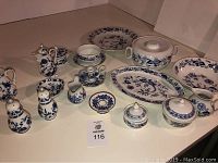 Photo of blue and white china set with various pieces arranged showing teapot, covered sugar bowl, creamers, salt and pepper shakers, platters, plates, bowls, cups and saucers with coordinated blue floral pattern on white porcelain.