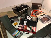 Full lot showing cassette case with tapes, books, vinyl records, retro radio, and electronic music equipment.