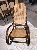 Front view of adult size rocking chair with rattan woven seat and backrest, bentwood frame with dark wood finish.