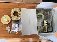 Box opened showing brass colored lock components with keys and instruction sheet.