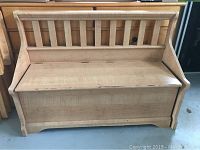 Front view of wooden hall bench showing slatted back and hinged seat closed.