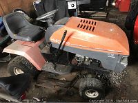 Left-side view of the lawn tractor showing steering wheel, seat, tires, and melted patched area on engine compartment plastic.