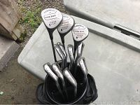 Golf clubs arranged in black vinyl bag showing 1, 3, 5 woods with Campbell labels and irons numbered 3 to 9 along with pitching wedge.