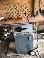 Front and side view of Rockwell Beaver table saw showing steel body, rusty blade and orange safety guard, with belt drive motor attached.