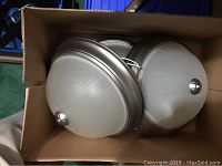 Five circular flush mount lights with frosted ribbed glass and gunmetal rims packed together in a cardboard box.