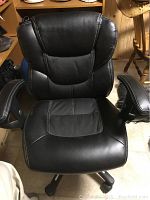 Top front view showing black leather-trimmed seat and backrest with mesh center insert and padded armrests with white stitching.