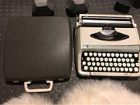 Smith Corona Pride Line manual typewriter with closed carrying case beside it on the floor.