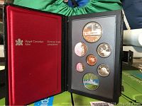 Leather bound coin proof set opened showing seven coins in display holder and red velvet lining with Royal Canadian Mint text