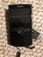 Front view of Kodak Zi8 video camera showing LCD screen, navigation buttons, and built-in USB connector.
