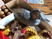 Wooden duck decoy with assorted wooden toys including rope for ring toss and a puzzle piece, all placed inside an open box.