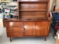 Front view of mid century wooden buffet and upper cabinet with drawers on left, doors on right, and empty upper shelving space