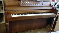 Full front view of Kimball upright piano showing wooden construction, keyboard, and pedal details.
