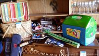 Photo showing two wicker baskets, striped cooler bag, green plastic cooler, wine backpack, corn roaster, beach mat, tablecloth and stadium seats.