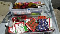Clear bin filled with assorted holiday gift bags, tags, tissue paper, bows, and other wrapping supplies shown from above