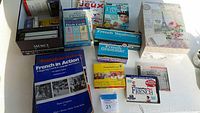 Image showing assorted French language learning materials including boxed flash cards, books, workbooks, and tapes on a table.
