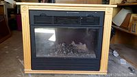 Front view of the Heat Surge electric fireplace showing the wood finish frame and glass window with simulated embers inside.