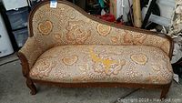 Front view of the vintage sofa showing the curved wood frame and paisley patterned upholstery with a large tear in the seat.