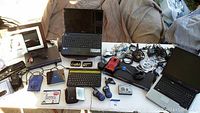 View of all items including laptops, walkie talkies, cables, external hard drives, photo frame, and other electronics arranged on a table.