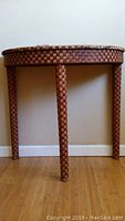 Front view of the semi-circle table showing three legs and plastic wicker pattern.